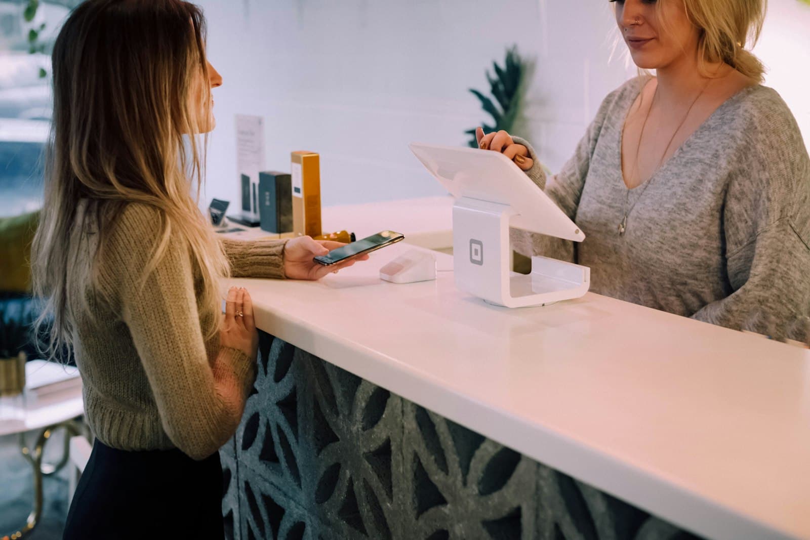 A customer paying at a shop counter on a tablet point-of-sale terminal